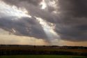 Sun shines through the clouds onto a corn field in Cynthiana, Indiana.