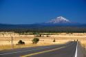 Automobiles travel on the highway near McArthur, California with a view of Mount Shasta in the background.