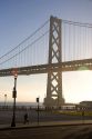 Foggy sunrise with the Bay Bridge backlit by the sun in the morning, San Francisco, California.