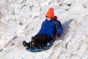 Boy sledding down a snow covered hill in Idaho. MR