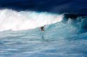 Surfing on waves in the pacific ocean off the island of Maui, Hawaii.