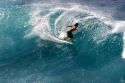 Surfing on waves in the pacific ocean off the island of Maui, Hawaii.