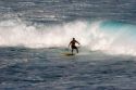 Surfing on waves in the pacific ocean off the island of Maui, Hawaii.