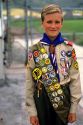 Boy scout in uniform with sash of badges.