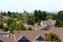 Rooftops of suburban sprawl housing with smog over the city of Boise, Idaho in the background.