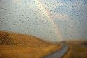 Rain drops on a car windshield with rainbow in the distance near Boise, Idaho.