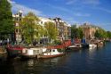 Row houses and canal boats on the Amstel River in Amsterdam, Netherlands.