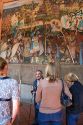 A tour guide showing tourists a mural painted by Diego Rivera at the National Palace in Mexico City, Mexico.