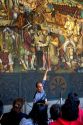 A tour guide showing tourists a mural painted by Diego Rivera at the National Palace in Mexico City, Mexico.