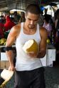 Hawaiian man cutting the husk off of a coconut at a market in Hilo on the Big Island of Hawaii.