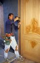 Carpenter using a cordless drill to install a door.