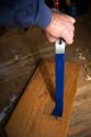 Flat pry bar pulling out a nail from a piece of lumber.