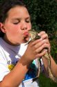11 year old girl kissing a bullfrog in Boise, Idaho. MR