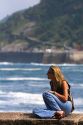 Woman sits on a seawall in the city of Donostia-San Sebastian, Guipuzcoa, Basque Country, Northern Spain.