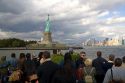 Tourists view the Statue of Liberty from New York Harbor in New York, USA.