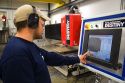 Worker using a computer to custom cut a granite countertop at the Shaker Hill Granite Company located in the town of Enfield, New Hampshire, USA.