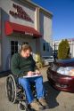 Handicapped insurance claims adjuster assessing the damage on an automobile in Boise, Idaho, USA. MR