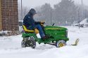 John Deere riding lawn mower fitted with a snow plow removing snow from a parking lot in Boise, Idaho, USA.