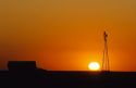 Windmill and barn silhouetted at sunset on farmland in western Kansas.