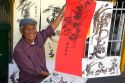 Vietnamese man drawing Chinese characters on red paper for good luck at the Giac Lam Pagoda Buddhist temple in Ho Chi Minh City, Vietnam.