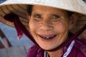 Portrait of an elderly Vietnamese woman whose teeth are stained from beetle nut wearing a tradional hat in Hoi An, Vietnam.