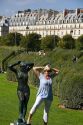 Visitor posing next to a statue at the Tuileries Garden near the Lourve in Paris, France.