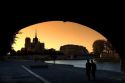 View of the Notre Dame cathedral at sunset through the arch of the Tournelle Bridge on the River Seine in Paris, France.