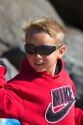Boy wearing sunglasses for ultraviolet protection along the D River in Lincoln City, Oregon, USA.