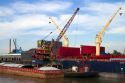 Crane loading a barge with coal on the Mississippi River at New Orleans, Louisiana, USA.