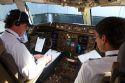 Pilot and first officer reviewing a pre-flight checklist in the cockpit of a Boeing 767 aircraft.