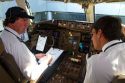Pilot and first officer reviewing a pre-flight checklist in the cockpit of a Boeing 767 aircraft.
