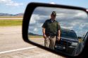 Wyoming Highway Patrol officer on seen in rear-view mirror along I-90 near the Wyoming, South Dakota border, USA. MR