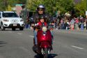 Father and son riding a scooter a the Trailing of the Sheep Parade on Main Street in Ketchum, Idaho, USA.