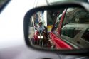 Motorbikes squeezing through car traffic seen through a rear view mirror in Bangkok, Thailand.