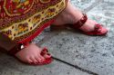 Woman wearing red jeweled sandals at the Temple of the Emerald Buddha located within the precincts of the Grand Palace, Bangkok, Thailand.