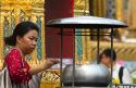 Woman lighting incense at the Temple of the Emerald Buddha located within the precincts of the Grand Palace, Bangkok, Thailand.