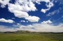 Cumulus clouds and blue sky over green fields near Pine, Idaho, USA.