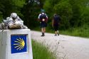 Pilgrims walk near a marker along the Camino De Santiago, the Way of St. James pilgrimage route, Navarra, Spain.