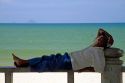 Man taking a nap on a bench at the beach in Nha Trang, Vietnam.