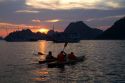 Tourists using sea kayaks at sunset in Ha Long Bay, Vietnam.