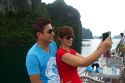 Vietnamese tourists taking a selfie aboard a tour boat in Ha Long Bay, Vietnam.