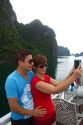 Vietnamese tourists taking a selfie aboard a tour boat in Ha Long Bay, Vietnam.