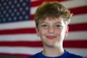 Ten year old american boy standing in front of an american flag in Charleston, South Carolina, USA. MR