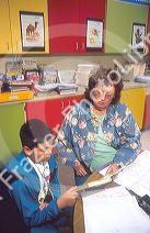 Elementary school teacher helping a male hispanic student in the classroom.  MR