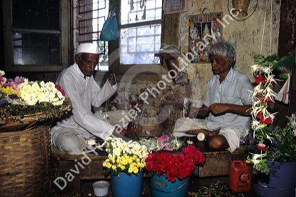 Street vendors stringing flowers in Mumbai, India.