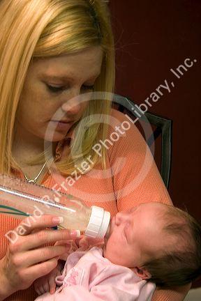 A mother feeding her newborn baby girl a bottle. MR