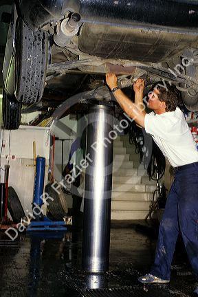 An auto mechanic working under a car on a hydraulic lift.