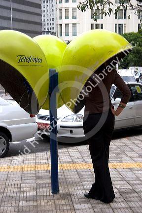 Woman using a public pay telephone in Sao Paulo, Brazil.