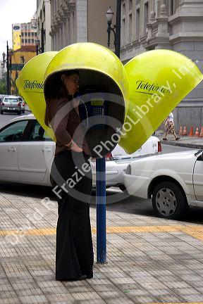 Woman talking on a public pay telephone in Sao Paulo, Brazil.