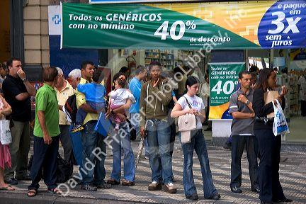 People standing in front of a store waiting for a bus in Sao Paulo, Brazil.